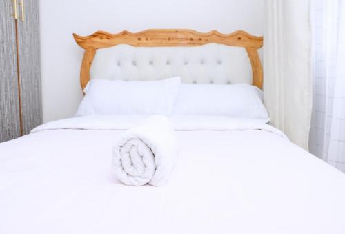 a bed with white sheets and a wooden headboard at Karani Suites in Nyahururu