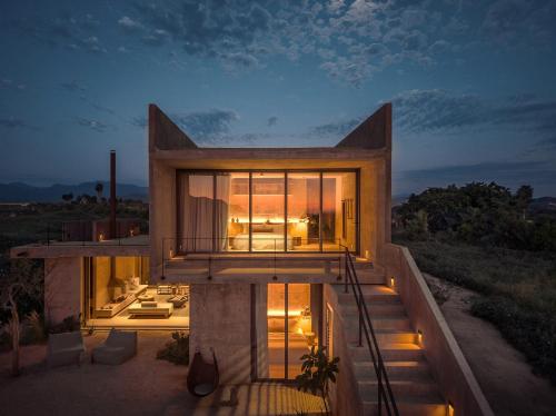 a house with glass doors and stairs on a hill at Paradero Todos Santos - Exclusive experiences included in Todos Santos