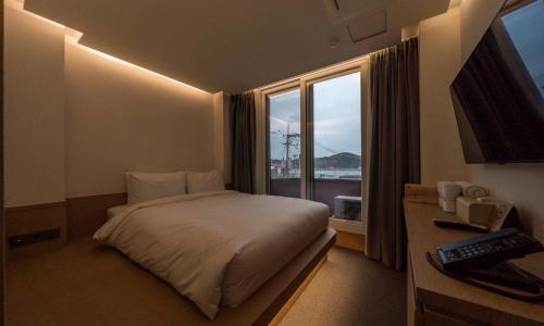 a hotel room with a bed and a window at Bluefrog Hotel in Incheon