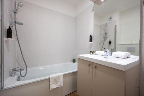 a white bathroom with a tub and a sink at Nemea Appart Hotel Sunset Nice Arenas in Nice