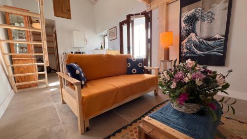 a living room with an orange couch and a vase of flowers at Casa Chula Estudio in Jimena de la Frontera