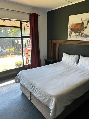 a bedroom with a large white bed and a window at Miners Rest Lodge in Phalaborwa