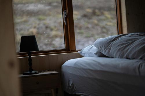 a bedroom with a bed and a window with a lamp at Paradise Cottages in Vík