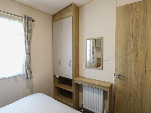 a bedroom with a bed and a mirror and a closet at Caravan 325 in Lowestoft
