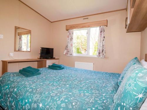 a bedroom with a bed with blue sheets and a window at The Oakley in Par