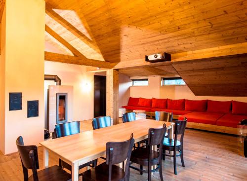 a dining room with a table and a red couch at alpen select lodge Kleinwalsertal in Riezlern