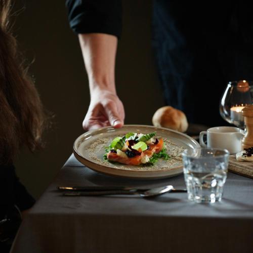 a person holding a plate of food on a table at Skálakot Manor Hotel in Hvolsvöllur
