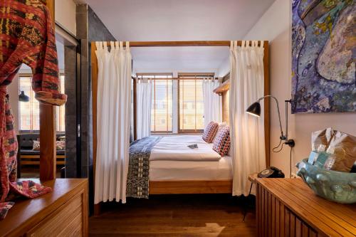 a bedroom with a canopy bed with a window at Manon Les Suites Guldsmeden in Copenhagen