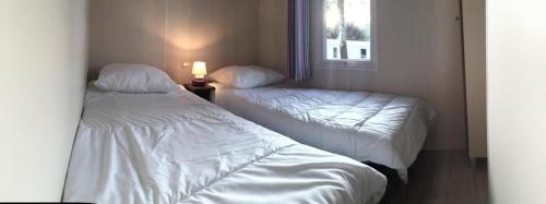 deux lits dans une petite pièce avec une fenêtre dans l'établissement Mobil-home 4 pers dans Camping 4 étoiles La Palmyre, à La Palmyre