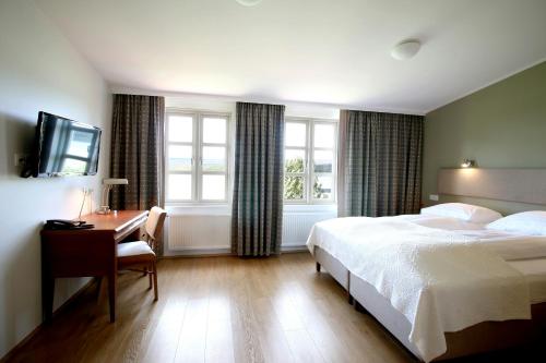 a bedroom with a bed and a desk and a television at Gistihúsið - Lake Hotel Egilsstadir in Egilsstaðir