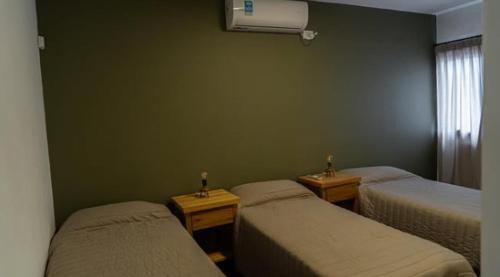 a room with two beds and a green wall at El descanso - Costa Azul in Villa Carlos Paz