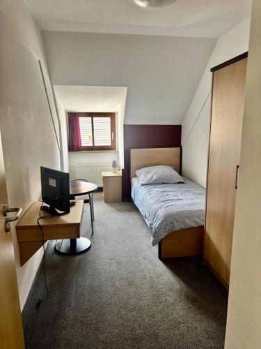 a bedroom with a bed and a desk with a computer at Neros Hotel in Siegenburg
