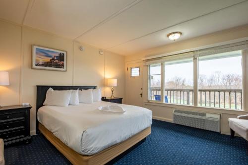 a bedroom with a large white bed and windows at Wonder View Inn - Bar Harbor Collection in Bar Harbor