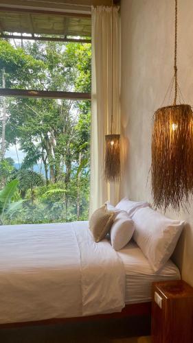 a bed with white pillows and a window in a room at Wild Wasi - Private Jungle Villa in Puyo