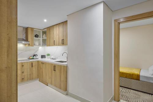 a kitchen with wooden cabinets and a bed at Makarem Haram view suites in Medina