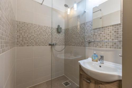 a bathroom with a glass shower and a sink at Zamárdi Parti Apartman in Zamárdi