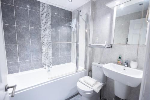 a bathroom with a toilet and a shower and a sink at Harbour Penthouse Whitby in Whitby