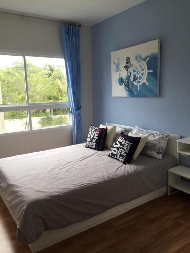 a bedroom with a bed with pillows and a window at The Trust Huahin By Sopida in Hua Hin