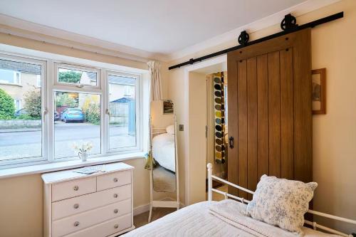 a bedroom with a bed with a dresser and a window at The Apartment at Charles Road in Frome