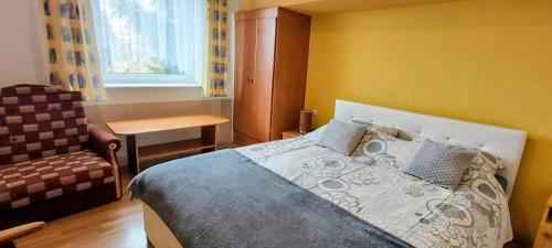 a bedroom with a bed and a chair and a window at Dom Pod Gruszą in Chmielno