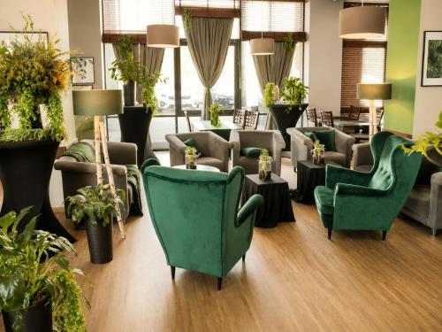 ein Wartezimmer mit grünen Stühlen und Pflanzen in der Unterkunft Great Polonia Silesian Quality Hotel in Kattowitz