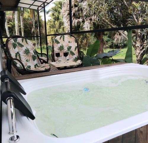 a bath tub with two chairs sitting in it at Cabaña con Jacuzzi Privado en El Peñol El palmar lodge in Chiquinquirá