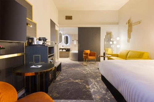 a hotel room with a bed and a living room at Le Grand Hôtel Dieu by SOWELL COLLECTION in Nîmes