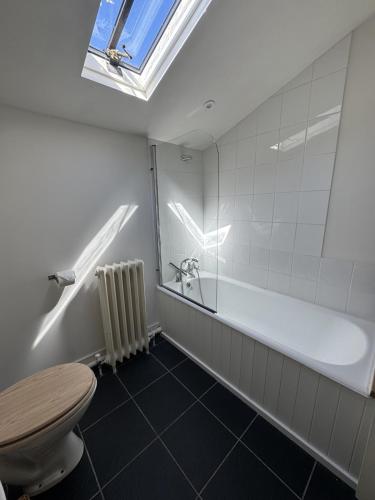 a bathroom with a tub and a toilet and a window at The Old Barn in Farthinghoe