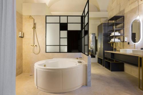a bathroom with a tub and a sink at Le Grand Hôtel Dieu by SOWELL COLLECTION in Nîmes
