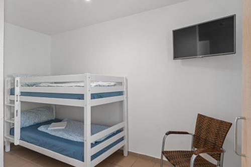 a white bunk bed with a chair and a flat screen tv at MK Apartments Delmenhorst nähe Bremen 20 in Delmenhorst