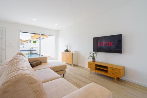 a living room with a couch and a flat screen tv at Villa Emilio with private pool in Mariquiteira