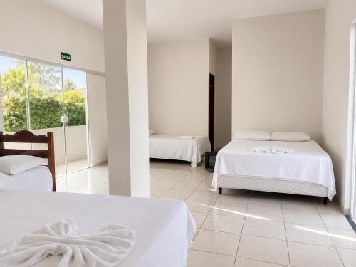 a bedroom with two beds with white sheets at Hotel Natureza in Anhanduí