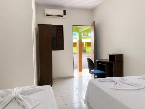 a bedroom with two beds and a desk and a door at Hotel Natureza in Anhanduí