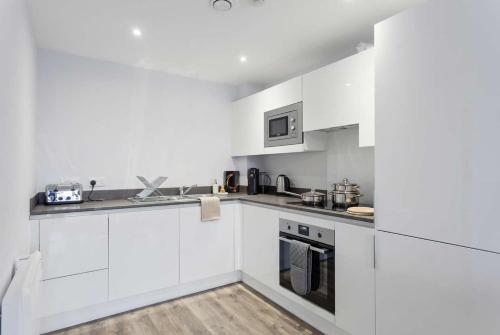 a white kitchen with white cabinets and appliances at Central Birmingham 2 BED Modern Spacious Apartment in Birmingham