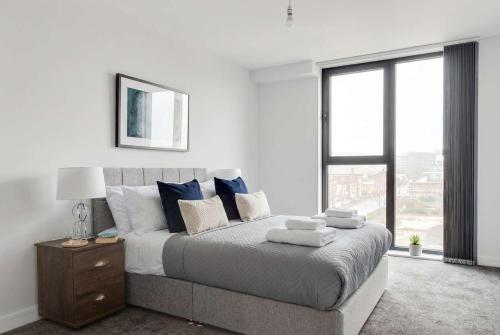 a bedroom with a bed with blue pillows and a window at Central Birmingham 2 BED Modern Spacious Apartment in Birmingham