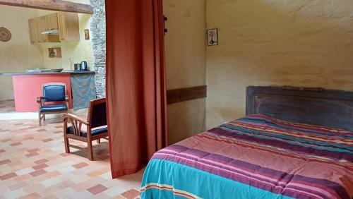 a bedroom with a bed and a chair and a kitchen at gite art et nature in Thorigny