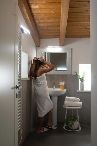 a woman standing in front of a sink in a bathroom at Hotel Ristorante Fontana in Calestano