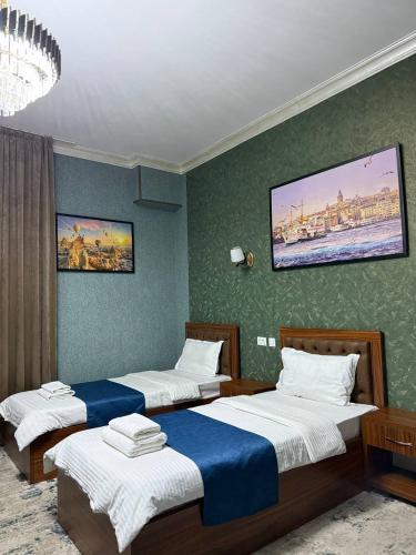 a bedroom with three beds and a painting on the wall at Almaz Hotel Uzbekistan in Tashkent