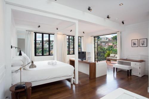a white bedroom with a bed and a desk with a television at Grand Hotel Urban in Antananarivo