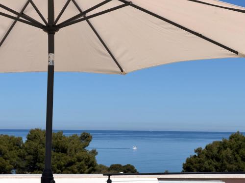 a white umbrella with the ocean in the background at Luxekey ETTORE HOUSE in Scopello