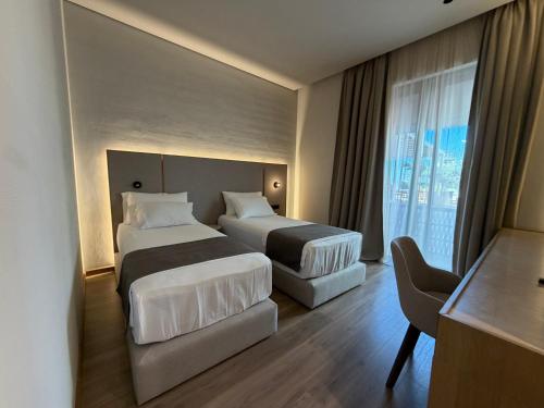 a hotel room with two beds and a desk at Riviera Boutique Hotel by Pomo d'oro in Vlorë