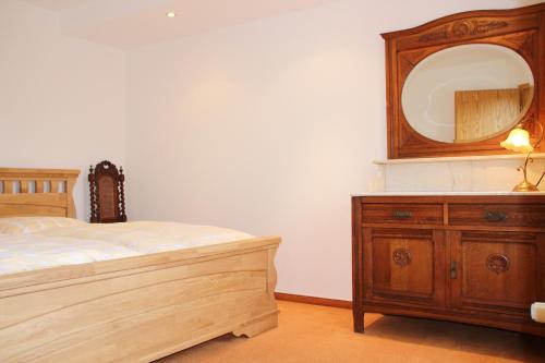 a bedroom with a wooden dresser and a mirror at Die gute Stube in Wernigerode