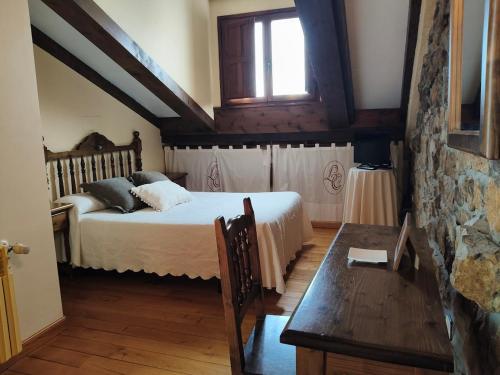 a bedroom with a bed and a table and a window at Posada La Colodra in Los Tojos