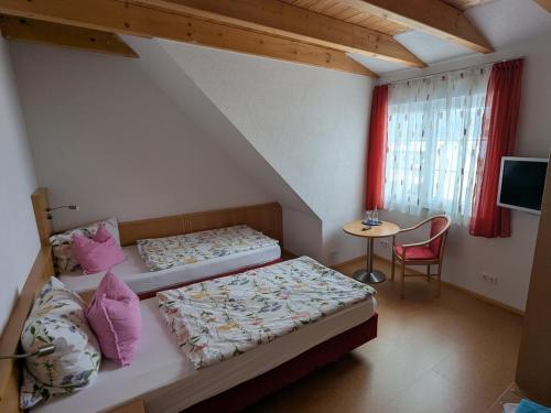 two beds in a room with a table and a window at Steakhüsli Hotel- Restaurant in Schopfheim
