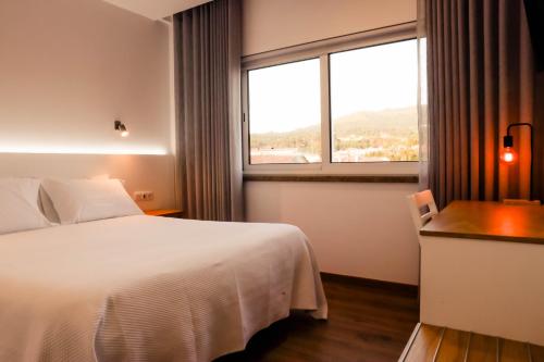 ein Hotelzimmer mit einem Bett und einem Fenster in der Unterkunft Hotel Flor do Minho in Valença