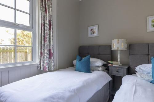 a bedroom with two beds and a window at Fordel Cottage in Dalkeith