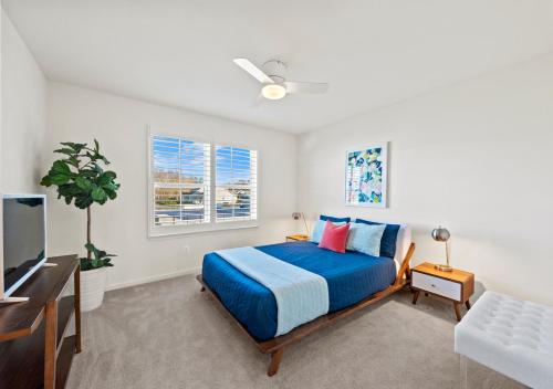 a bedroom with a blue bed and a tv at Modern Townhouse with Pool Gym & Tennis Near Beach in Ocean View