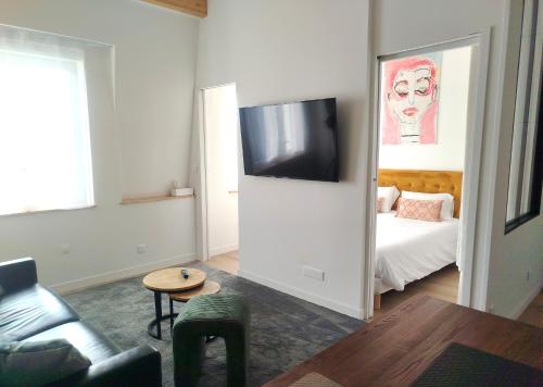 a living room with a couch and a tv on a wall at Studio à la VILLA VOLTAIRE in Clamart