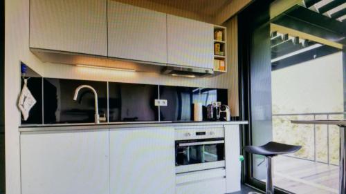 une cuisine avec des armoires blanches, un évier et une cuisinière dans l'établissement Studio Avec Terrace DOCKS, à Strasbourg