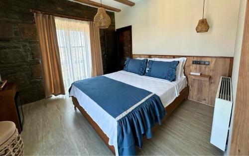 a bedroom with a large bed with blue pillows at Mathilda Gökçeada in Gokceada Town